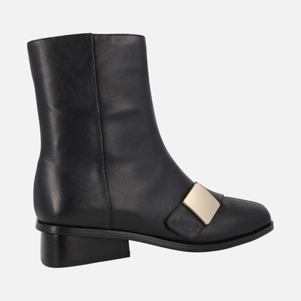 Botines en piel negra con tacón bajo y chapa dorada